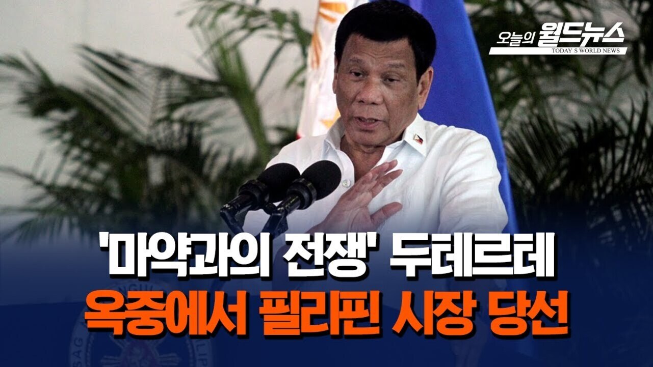 한 남성이 연단에서 마이크 앞에 서서 손을 들어 발언하고 있으며, 화면 하단에는 '마약과의 전쟁' 두테르테 옥중에서 필리핀 시장 당선이라는 문구가 있다.