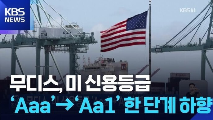 미국 국기가 걸린 항구 크레인과 선박이 보이며, 'KBS NEWS' 로고와 함께 '무디스, 미 신용등급 Aaa→Aa1 한단계 하향'이라는 자막이 있다.