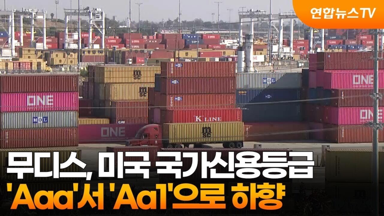 컨테이너 야적장에 여러 개의 컨테이너가 쌓여 있고, 화면 하단에는 '무디스, 미국 국가신용등급 'Aaa'서 'Aa1'으로 하향'이라는 자막이 있다.