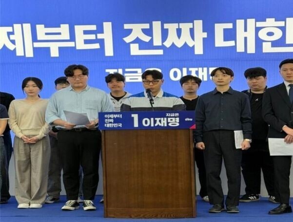 여러 명의 남녀가 무대 위에 서 있고, 중앙에는 연단에서 마이크를 잡고 있는 남성이 있다. 배경에는 '제부터 진짜 대한'이라는 큰 글씨가 보인다.