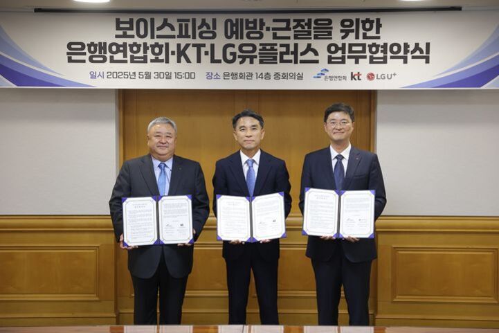 정장 차림의 세 남성이 '보이스피싱 예방·근절을 위한 은행연합회·KT·LG유플러스 업무협약식' 현수막 아래에서 협약서를 들고 기념촬영을 하고 있다.