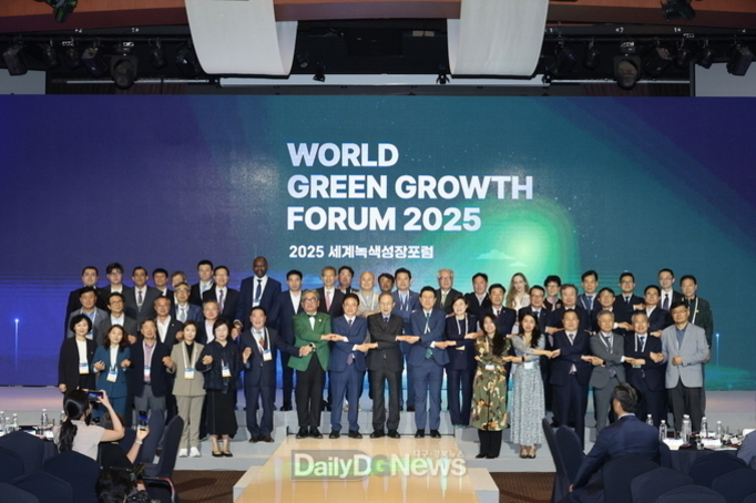 여러 명의 남녀가 무대 위에서 단체로 포즈를 취하고 있으며, 배경에는 'WORLD GREEN GROWTH FORUM 2025'와 '2025 세계녹색성장포럼'이라는 문구가 보인다.