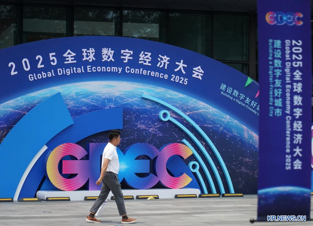한 남성이 '2025 글로벌 디지털 경제 대회(Global Digital Economy Conference 2025)'라고 적힌 대형 안내판 앞을 걷고 있다.