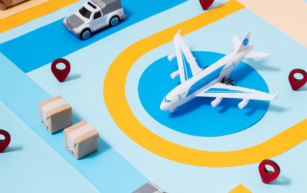 장난감 비행기, 트럭, 상자와 지도 위에 위치 표시 아이콘이 놓여 있는 물류 및 운송 개념 이미지