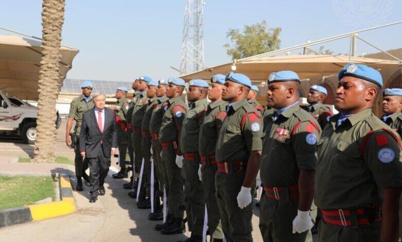유엔 평화유지군 제복을 입은 군인들이 파란색 베레모를 쓰고 일렬로 서 있으며, 한 남성이 이들을 점검하고 있다.