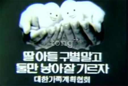 두 손에 하얀 인형 두 개를 들고 있으며, 아래에는 '딸아들 구별말고 둘만 낳아 잘 기르자 대한가족계획협회'라는 문구가 적혀 있다.