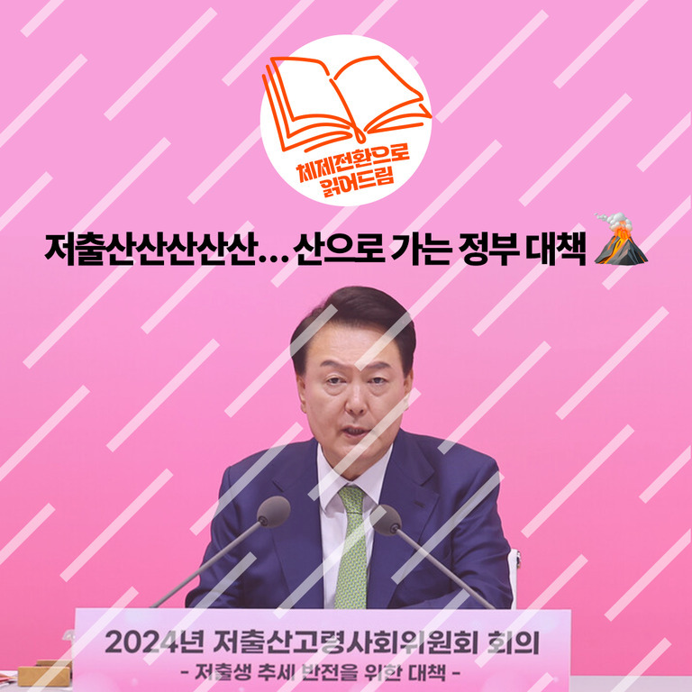 분홍색 배경 앞에서 마이크가 설치된 책상에 앉아 있는 남성이 2024년 저출산고령사회위원회 회의에서 발언하고 있다. 상단에는 '저출산산산산산... 산으로 가는 정부 대책'이라는 문구와 화산 이모지가 있으며, 왼쪽 위에는 '체제전환으로 맡아드림'이라는 글자가 적힌 책 아이콘이 있다.