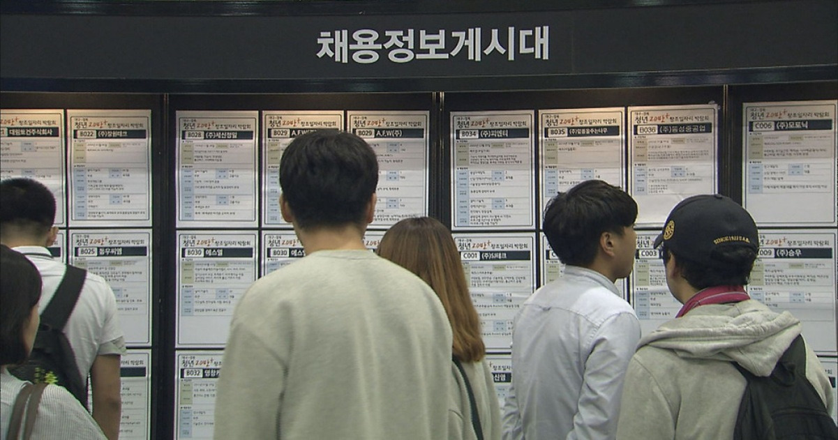 여러 명의 사람들이 채용정보게시대 앞에서 구인 공고를 살펴보고 있다.