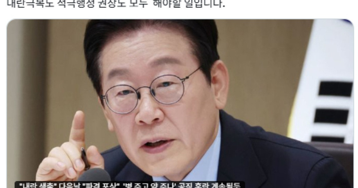안경을 쓴 남성이 회의실에서 손가락을 들어 발언하는 모습. 배경에 태극기 일부가 보임.